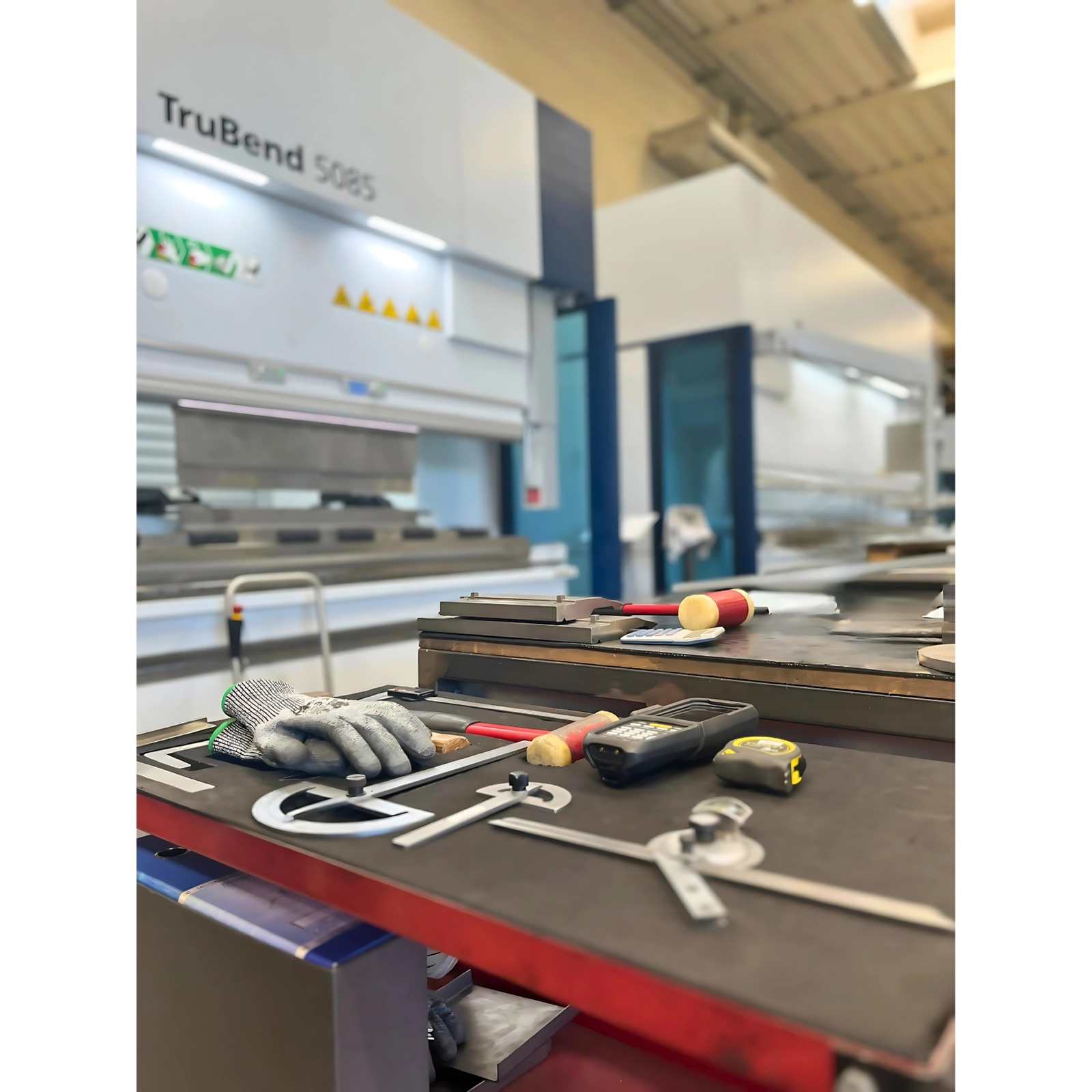 Banco di lavoro con attrezzi accanto alla presso-piega TruBend nello stabilimento Laser Tech